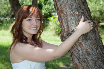 Red hair bride in a wedding dress outside holding tree