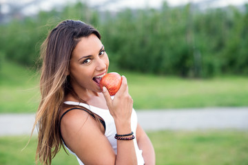 Junge Frau beisst in einen gesunden Apfel und lacht glücklich dabei