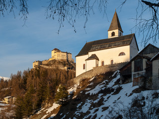 Fototapeta na wymiar Small rural church and castle on the background in Tarasp village, Graubunden, Switzerland