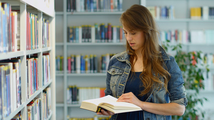 A young woman in a public library. It's her leisure time and she is looking for some good books to read. 