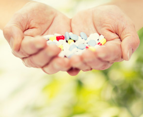 close up of senior woman hands with pills