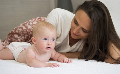 Mother and baby daughter on bed
