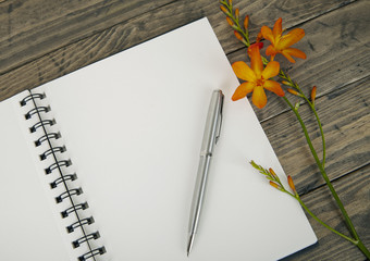 An open blank sketchbook with flowers on a wooden desktop