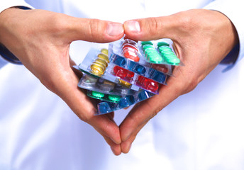 A young doctor holds the patient's hand with pills