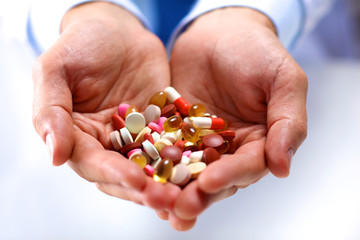 A young doctor holds the patient's hand with pills