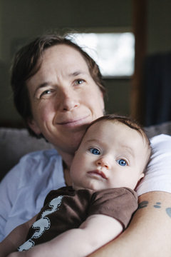 A woman holding a young six month old baby. 