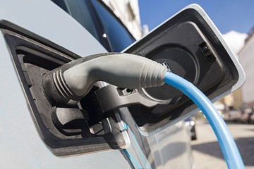 Power supply for electric car charging. Electric car charging station. Close up of the power supply plugged into an electric car being charged.