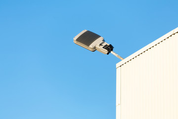 Modern industrial lamp on a building against sky.