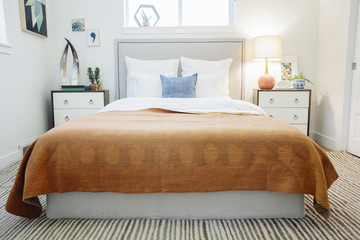 A bedroom in an apartment with a double bed and a retro look antique patterned patchworked bed cover. 