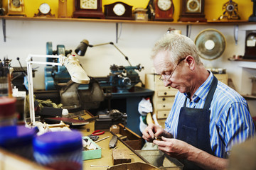 A clock maker busy in his workshop. 