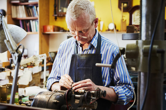 A clock maker busy in his workshop. 
