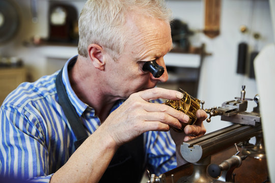 A clock maker busy in his workshop. 