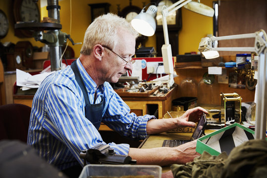 Clockmaker using a laptop in workshop