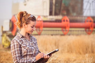Pretty farmer girl in glasses with hair tied in a ponytail keeps a harvest accounting in the...