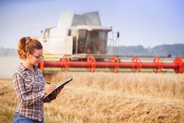 Agronomist girl in glasses with hair tied in a ponytail keeps a harvest accounting in the folder....