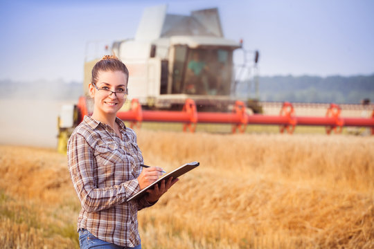 Pretty farmer girl in glasses with hair tied in a ponytail keeps a harvest accounting in the folder. Sunny day. Horizontal. Image released. Image released.