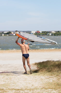 Man carries a windsurfing board