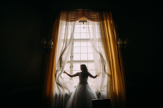 Silhouette of beautiful bride in front window