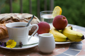Breakfast with cup of coffee and croissant, bread and fruits in background