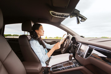 happy woman driving car with smarhphone