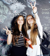 back to school after summer vacations, two teen real girls in classroom with blackboard painted together