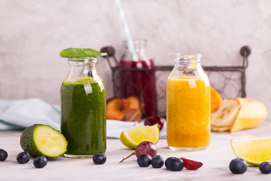 Green, yellow and purple smoothies over stone table