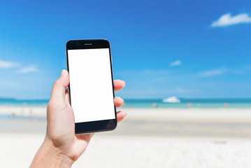 Beautiful woman's hand using smart phone at beach. Smartphone white screen at sea.