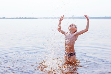 boy enjoys swimming in the river. the child splashing in river. the concept of a happy childhood.