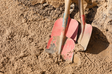 Drei Schaufeln stehen im Sand auf einer Strassenbaustelle