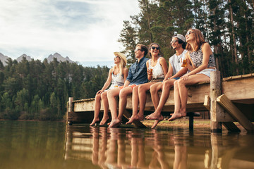 Group of friends sitting on jetty at lake