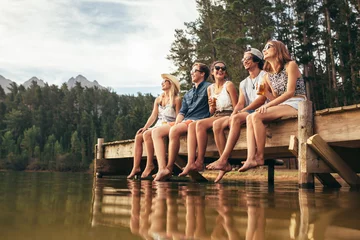 Fotobehang Group of friends sitting on jetty at lake © Jacob Lund