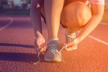 Female athlete tying laces for jogging , sunset