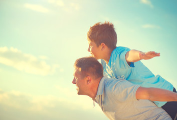 Happy father and son having fun over beautiful sky outdoors