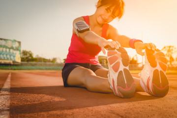Female athlete tying laces for jogging , sunset