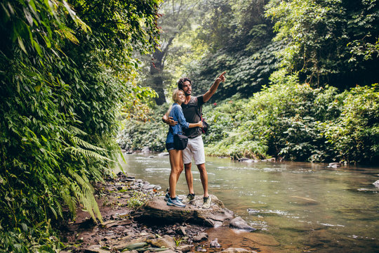 Hiking couple by stream looking at a view