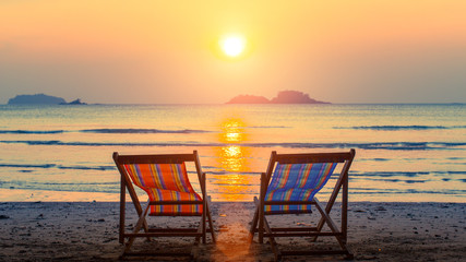 Pair of beach loungers on the deserted beach at sunset. - 116955257
