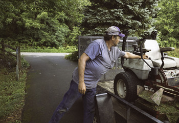 Man loading lawnmower on trailer