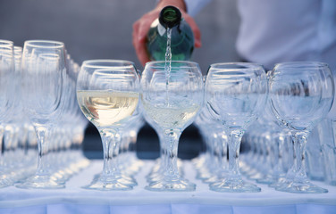 The waiter pours wine into a glass