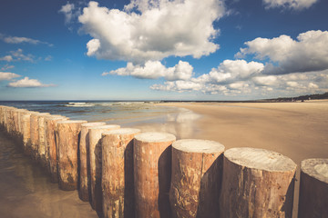 Wooden breakwaters on sandy Leba beach in late afternoon, Baltic