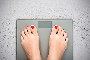 Help to lose kilograms with woman feet stepping on a weight scale - obrazy, fototapety, plakaty