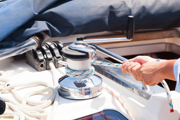 Sailing crew member pulling rope on sailboat