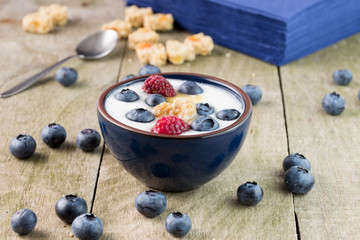 Bowl of whole blueberries in white yogurt on rustic wooden table.