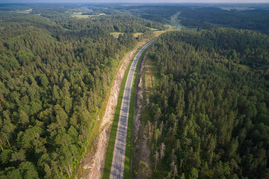 aerial view of car driving on a road in the woods