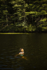 Fototapeta na wymiar Girl swimming in lake at wood