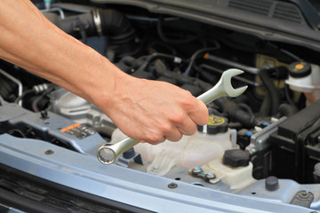 Car service concept, Mechanic Hand Hold Spanner Tool, man checking the condition of car engine.