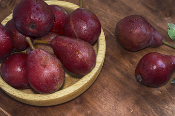 Ripe red pear in a wooden plate