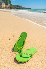 Fototapeta na wymiar Womens green sandals on tropical beach