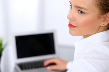 Business woman is typing on laptop computer. Bookkeeper or female financial inspector  making report, calculating or checking balance.