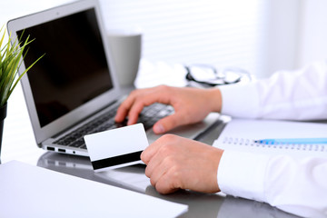 Close up of business woman hands using credit card and laptop computer