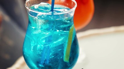 Close up on icy cold blue beverage with fruit slice and matching straw with copy space